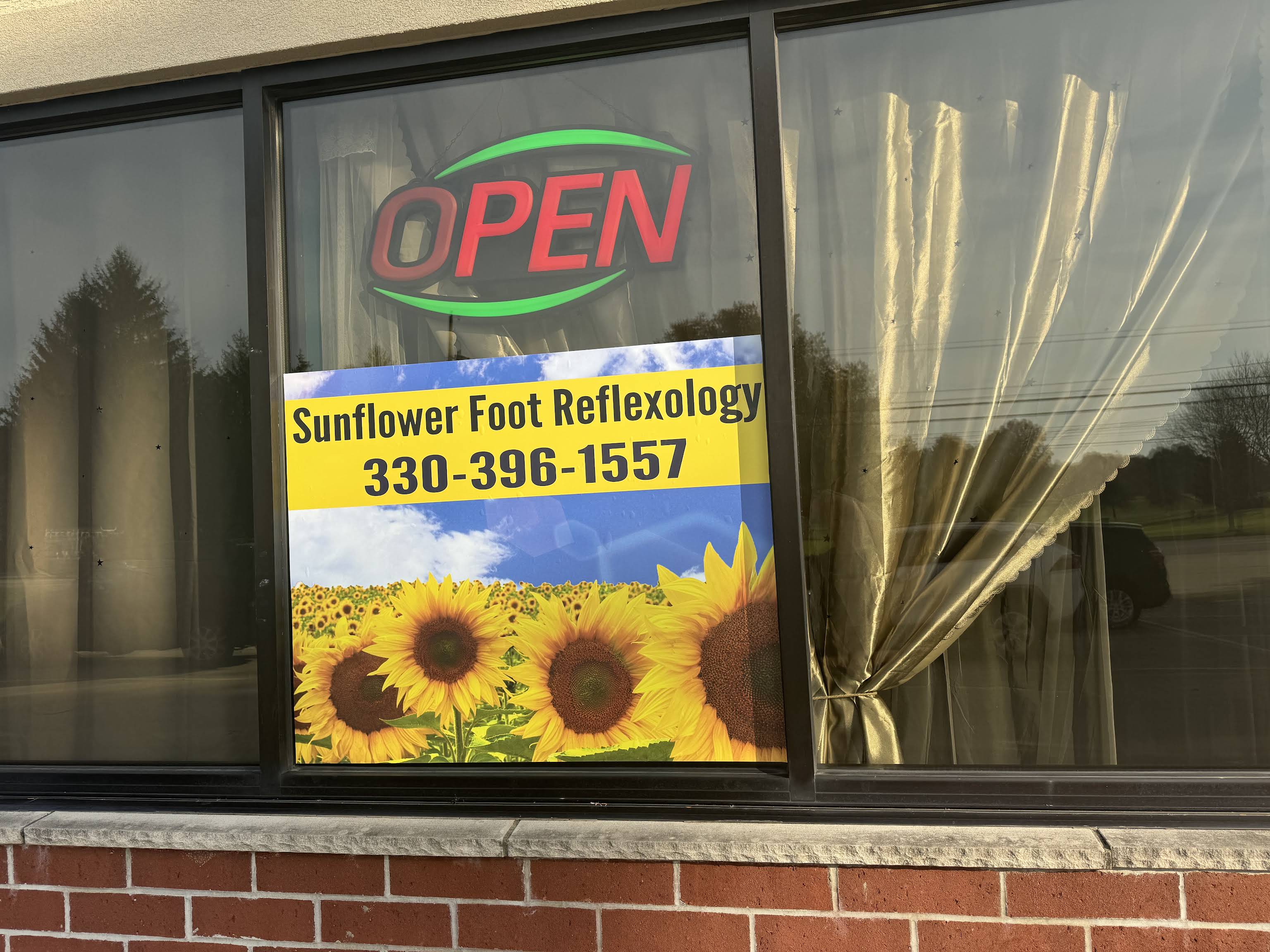 Sunflower Foot Reflexology’s storefront window and sunflower sign